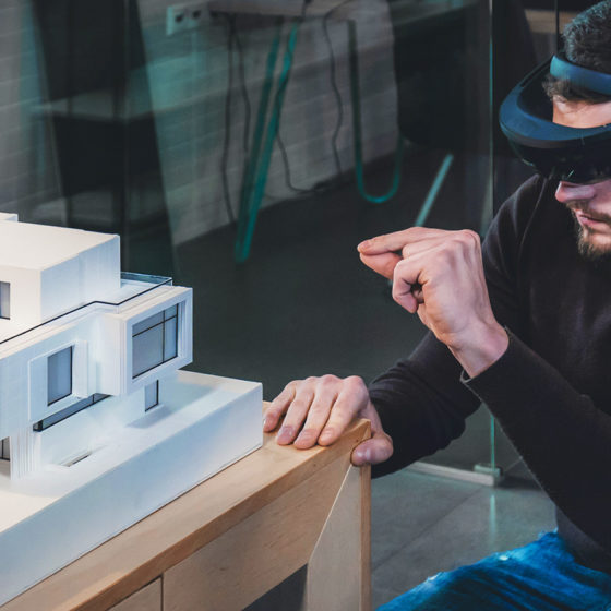 male architect working on a private house project in the office using augmented reality glasses