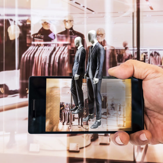 Hand holding smart phone with A/R application on screen to finding interested product in a retail store