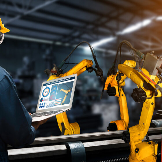 Smart factory engineer using automation technology to control robotic arms on a tablet